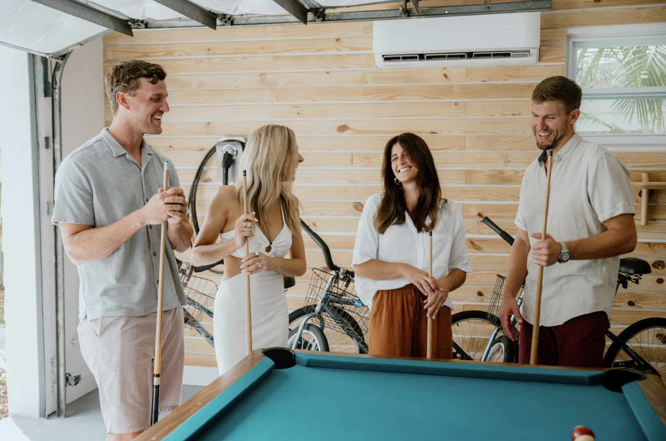 Group of women in light colored robes laughing together in a bright vacation rental living space